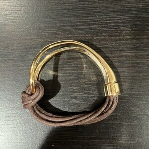 Gold bracelet with brown string and metal clip opening